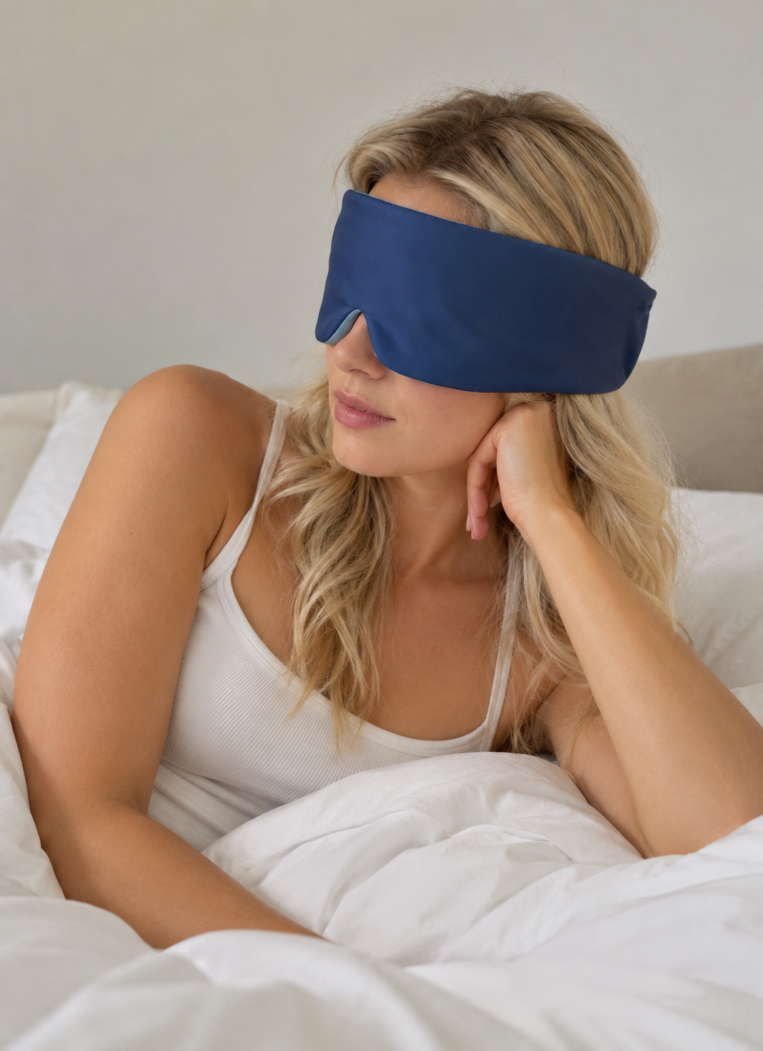 Woman relaxing in bed wearing the Lune Mask 3.0 blackout sleep mask